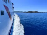 Traghetto in navigazione verso l'isola d'Elba, con la costa all'orizzonte sotto un cielo azzurro.