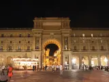 La piazza della Repubblica a Firenze di notte, con il suo arco monumentale illuminato, gente che passeggia e una giostra scintillante.