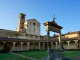 Cortile con pozzo e campanile di Castel Nuovo Berardenga, sotto un cielo azzurro.