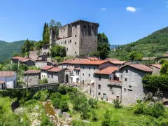 Fivizzano cosa vedere: un borgo medievale con castello, case in pietra e un ponte ad arco su un ruscello.