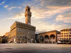 Il maestoso Palazzo Vecchio domina Piazza della Signoria, con la sua torre imponente che svetta sotto un cielo al tramonto.