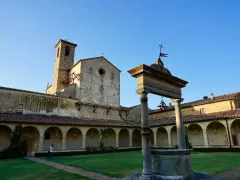 Cortile con pozzo e campanile di Castel Nuovo Berardenga, sotto un cielo azzurro.