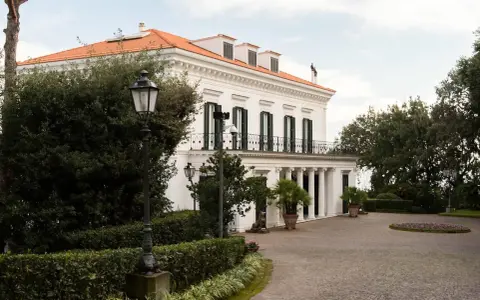 Villa signorile a San Giorgio a Cremano, con tetto arancione, colonne bianche e un viale acciottolato.