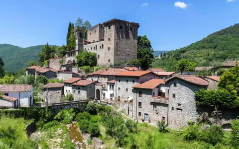 Fivizzano cosa vedere: un borgo medievale con castello, case in pietra e un ponte ad arco su un ruscello.