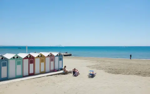 Colorate cabine sulla spiaggia di Ostia, mare di Roma, con persone che si rilassano al sole.