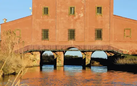 Edificio storico con ponticello ad archi sull'acqua, un'idea di cosa vedere vicino a Castiglione della Pescaia.