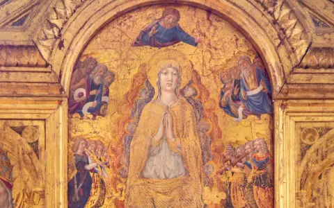 Dettaglio dorato del Duomo di Pienza: la Vergine in preghiera, circondata da santi e angeli musicanti, sotto un Cristo benedicente.