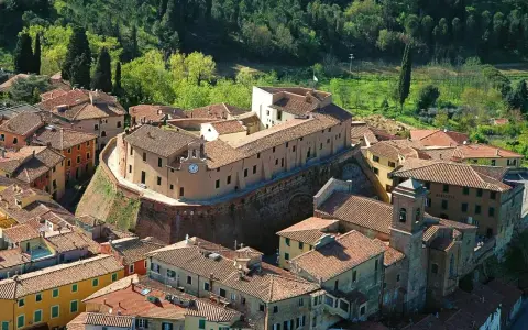 Borgo fortificato con case in pietra e tetti rossi, un campanile e un orologio. Un'ottima meta per scoprire cosa vedere vicino Pisa.