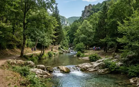 Sentiero in un bosco lussureggiante, con un fiume cristallino e una cascata. Coppia passeggia, un gruppo fa picnic. Un assaggio dei **parchi naturali Campania**.