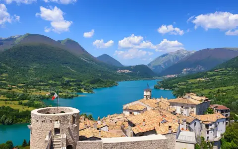 Villetta Barrea: cosa vedere? Un borgo con torre medievale, tetti rossi e un lago azzurro circondato da montagne verdi.