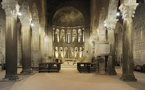 Interno della pieve di Gropina, con imponenti colonne, archi e un'abside decorata.