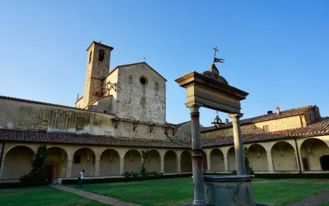 Cortile con pozzo e campanile di Castel Nuovo Berardenga, sotto un cielo azzurro.