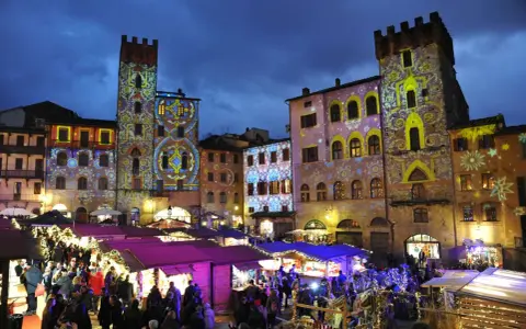 Mercatino natalizio ad Arezzo, con palazzi illuminati da proiezioni colorate. Vale la pena visitare Arezzo per questa magica atmosfera.