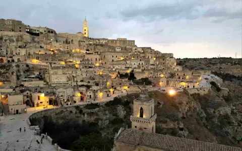 I Sassi di Matera illuminati al crepuscolo, un panorama mozzafiato di case scavate nella roccia e chiese antiche.