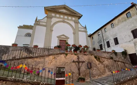 Terricciola cosa vedere: la chiesa parrocchiale domina la piazza, con un'antica croce e festoni colorati che creano un'atmosfera suggestiva.