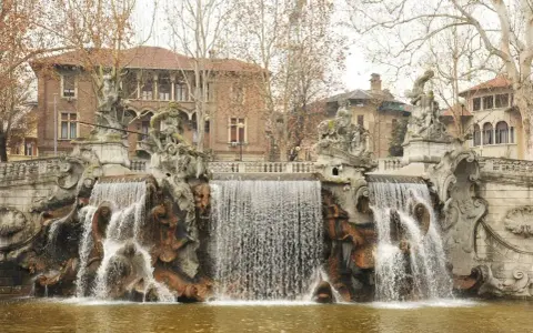 Fontana monumentale nel Parco del Valentino, con statue e cascate d'acqua che scendono su rocce scultoree.