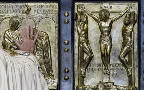Mano che tocca la porta santa San Pietro, con scene della crocifissione e del rinnegamento di Pietro.