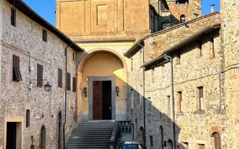 Chianni cosa vedere: un vicolo con case in pietra, una chiesa con un grande portale in legno e una scalinata.