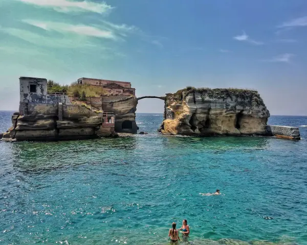 L'isola di Gaiola, con le sue rovine suggestive e il mare cristallino, accoglie bagnanti e nuotatori in una giornata di sole.