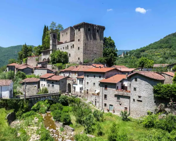 Fivizzano cosa vedere: un borgo medievale con castello, case in pietra e un ponte ad arco su un ruscello.