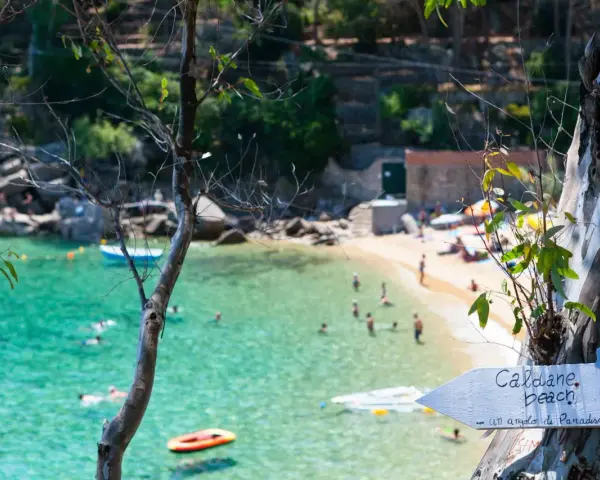 Segnale per le spiagge di Caldane, Isola del Giglio, indica un angolo di paradiso con gente che nuota nell'acqua cristallina.