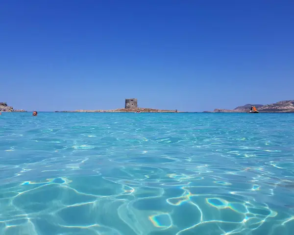 Acque cristalline e un'antica torre su un isolotto: ecco la spiaggia più bella d'Italia, un paradiso azzurro.