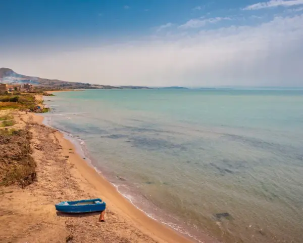 Spiaggia di Licata con barca blu e mare calmo. Un paesaggio da esplorare, tra terra e acqua cristallina.