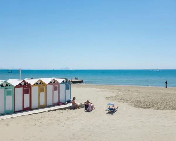 Colorate cabine sulla spiaggia di Ostia, mare di Roma, con persone che si rilassano al sole.