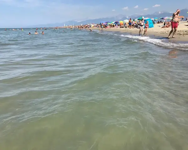 Onde leggere accarezzano la **spiaggia libera Viareggio**, affollata di bagnanti sotto ombrelloni colorati.