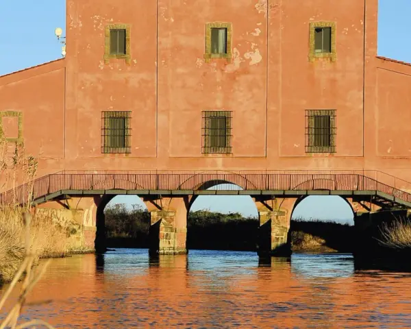 Edificio storico con ponticello ad archi sull'acqua, un'idea di cosa vedere vicino a Castiglione della Pescaia.