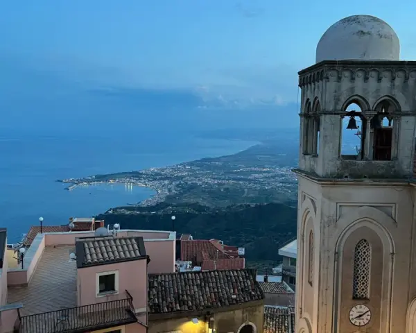 Castelmola cosa vedere: vista panoramica sul mare e sulla costa siciliana, con un campanile in primo piano.