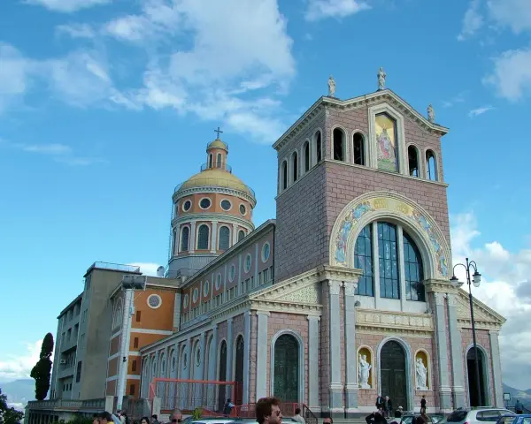 Imponente Santuario di Tindari con cupola dorata e facciata decorata, sotto un cielo azzurro con nuvole bianche.