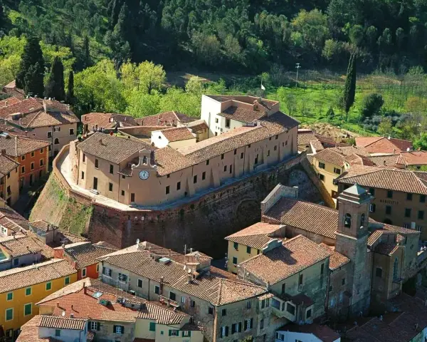 Borgo fortificato con case in pietra e tetti rossi, un campanile e un orologio. Un'ottima meta per scoprire cosa vedere vicino Pisa.