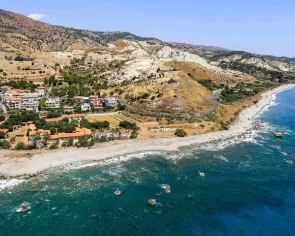 Paesaggio mozzafiato sulla costa ionica Calabria: case con tetti rossi, spiaggia rocciosa e mare blu intenso.