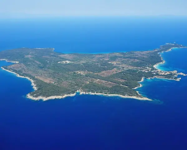 Vista aerea di un'isola verdeggiante, un'isola vicino all'Elba, con acque blu intenso e una piccola isola rocciosa in lontananza.