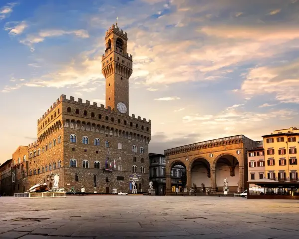 Il maestoso Palazzo Vecchio domina Piazza della Signoria, con la sua torre imponente che svetta sotto un cielo al tramonto.