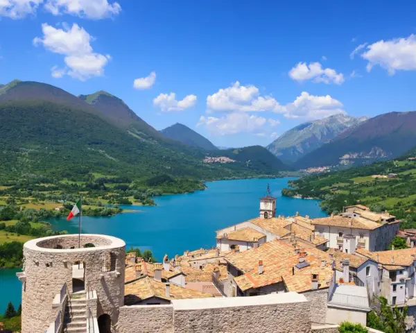 Villetta Barrea: cosa vedere? Un borgo con torre medievale, tetti rossi e un lago azzurro circondato da montagne verdi.