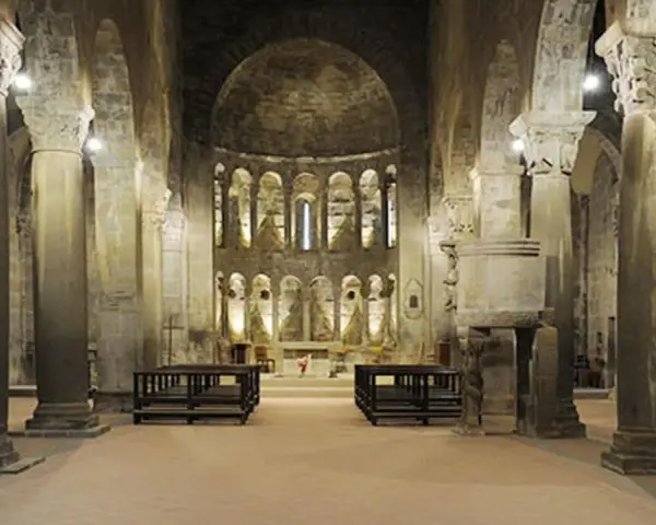 Interno della pieve di Gropina, con imponenti colonne, archi e un'abside decorata.