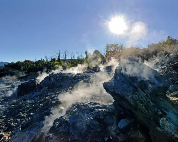 Fumarole attive nel **Val di Cecina**, con vapore che sale tra le rocce sotto un sole splendente.