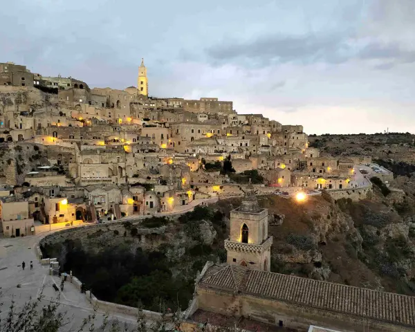 I Sassi di Matera illuminati al crepuscolo, un panorama mozzafiato di case scavate nella roccia e chiese antiche.