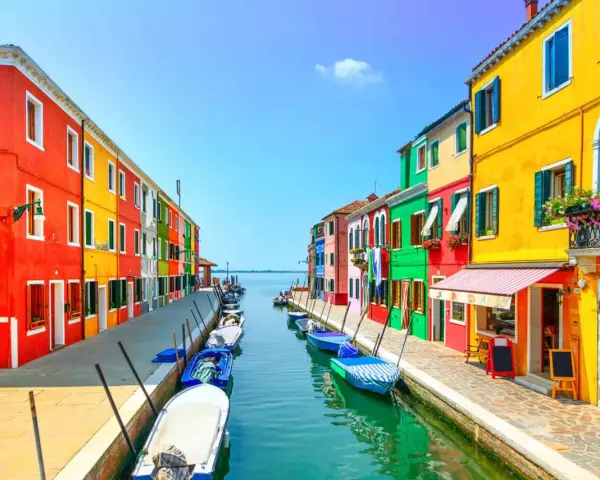 Coloratissime case affacciate su un canale, con barche ormeggiate. Un'immagine che invita a scoprire le splendide venezia isole da visitare.