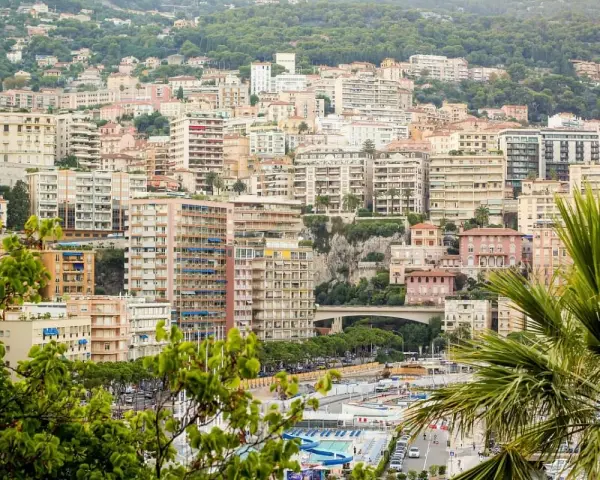 Vista panoramica del montecarlo centro storico, con palazzi color pastello e vegetazione lussureggiante che scende verso il mare.