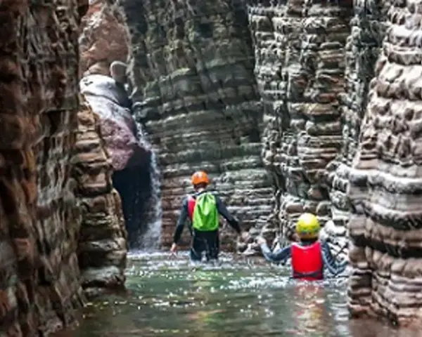 Esploratori in un canyon, tra rocce stratificate e acqua limpida, attraversano i **stretti di giaredo**.