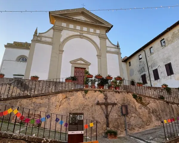 Terricciola cosa vedere: la chiesa parrocchiale domina la piazza, con un'antica croce e festoni colorati che creano un'atmosfera suggestiva.