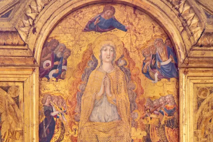 Dettaglio dorato del Duomo di Pienza: la Vergine in preghiera, circondata da santi e angeli musicanti, sotto un Cristo benedicente.