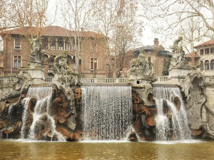 Fontana monumentale nel Parco del Valentino, con statue e cascate d'acqua che scendono su rocce scultoree.