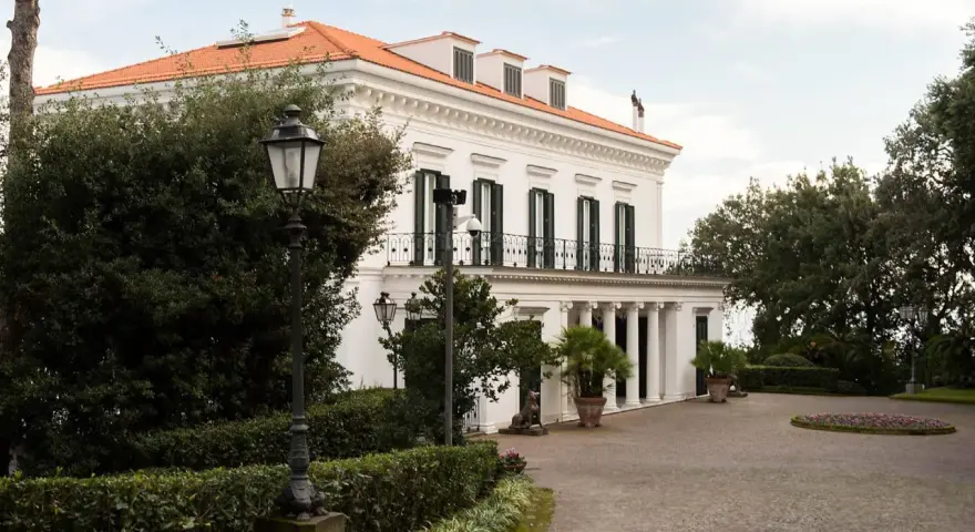 Villa signorile a San Giorgio a Cremano, con tetto arancione, colonne bianche e un viale acciottolato.