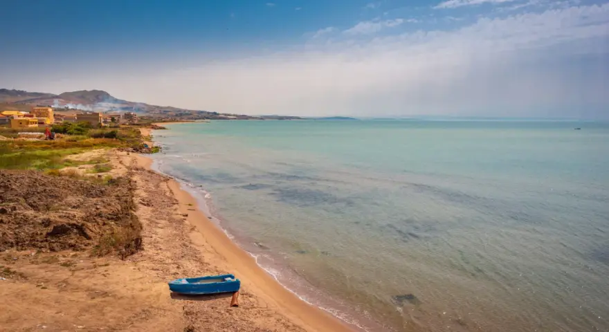 Spiaggia di Licata con barca blu e mare calmo. Un paesaggio da esplorare, tra terra e acqua cristallina.