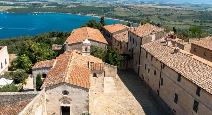 Antico borgo di Populonia centro storico, con vista sul golfo e colline verdi.