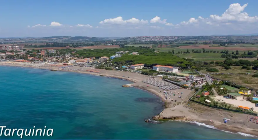 Vista aerea del lido di Tarquinia con spiaggia attrezzata, mare azzurro e pineta.